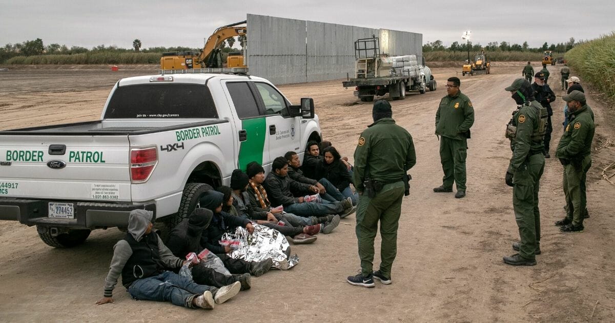 Border Patrol agents detain illegal immigrants caught near a section of privately built border wall under construction on Dec. 11, 2019, near Mission, Texas.
