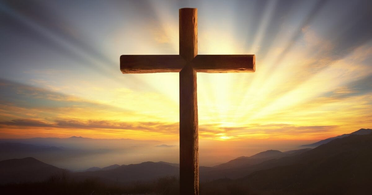 A stock photo of a Christian cross is seen above.