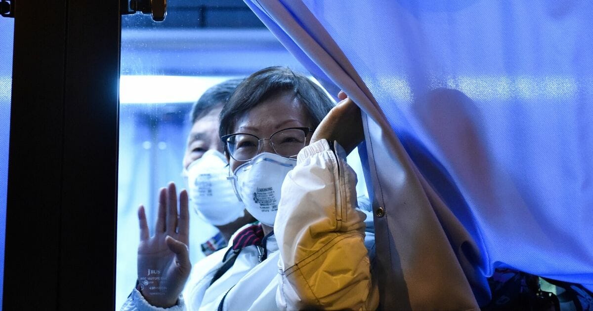 A U.S. passenger waves to reporters while arriving at the Haneda Airport, in Tokyo, on Feb. 17, 2020, after disembarking in Yokohama from the Diamond Princess cruise ship, where people are quarantined onboard due to fears of the new COVID-19 coronavirus.