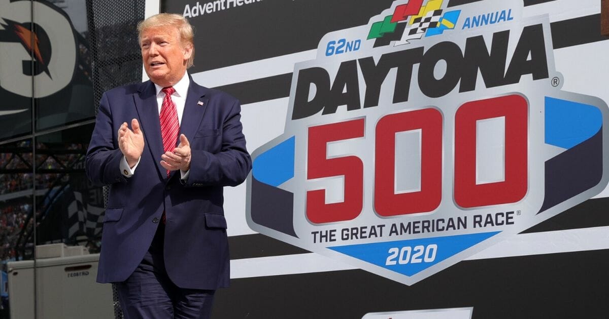 President Donald Trump speaks as first lady Melania Trump looks on from Victory Lane prior to the NASCAR Cup Series 62nd Annual Daytona 500 at Daytona International Speedway on Feb. 16, 2020, in Daytona Beach, Florida.