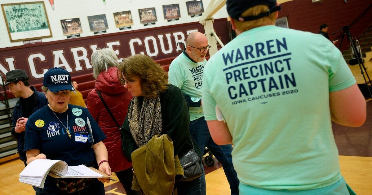 Precinct members for Democratic presidential candidate Sen. Elizabeth Warren try to sway an undecided voter during caucusing at Abraham Lincoln High School in Des Moines, Iowa, on Feb. 3, 2020.