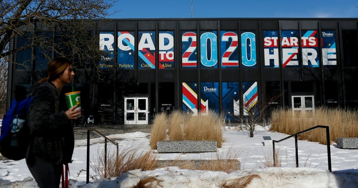 A woman walks past a sign displayed on a building at Drake University in Des Moines, Iowa, that reads "Road To 2020 Starts Here" on Feb. 2, 2020, the day before the Iowa caucuses.