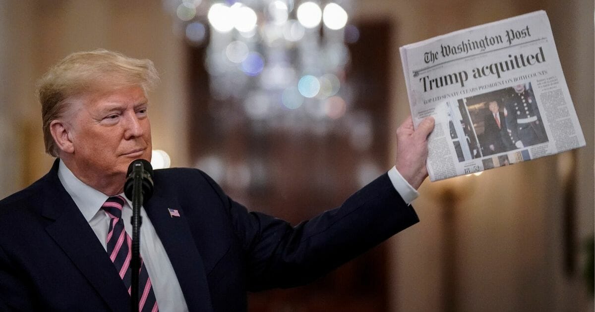 President Donald Trump holds a copy of The Washington Post as he speaks in the East Room of the White House on Feb. 6, 2020.