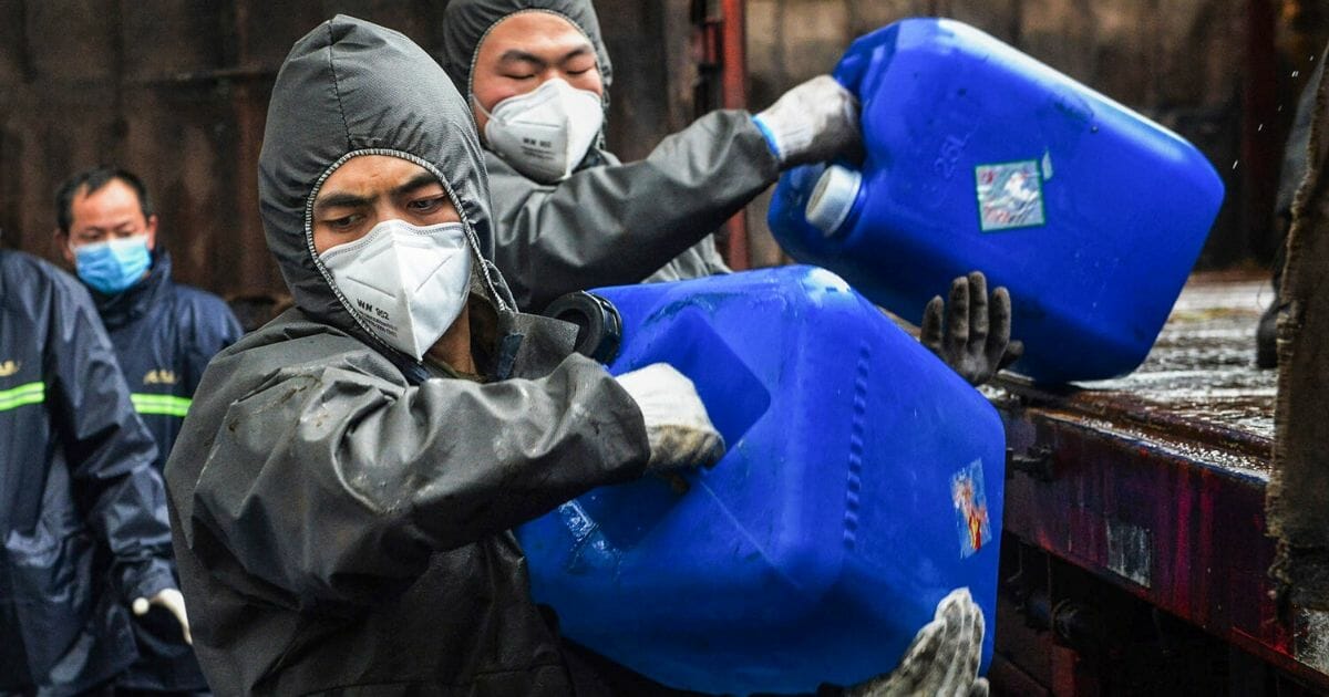 Chinese paramilitary police officers wearing protectieve gears transfer pails of disinfectant in Yunmeng county, outside Xiaogan City in China's central Hubei province on Feb. 12, 2020.