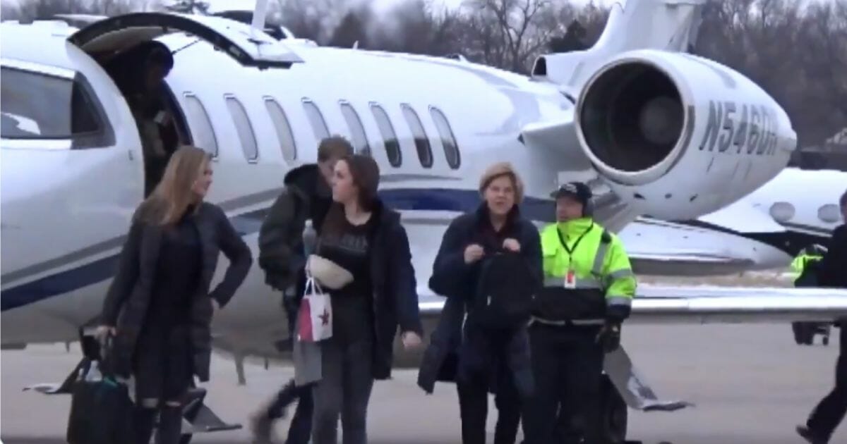 Elizabeth Warren disembarking a private jet, shortly before attempting to hide from a camera.