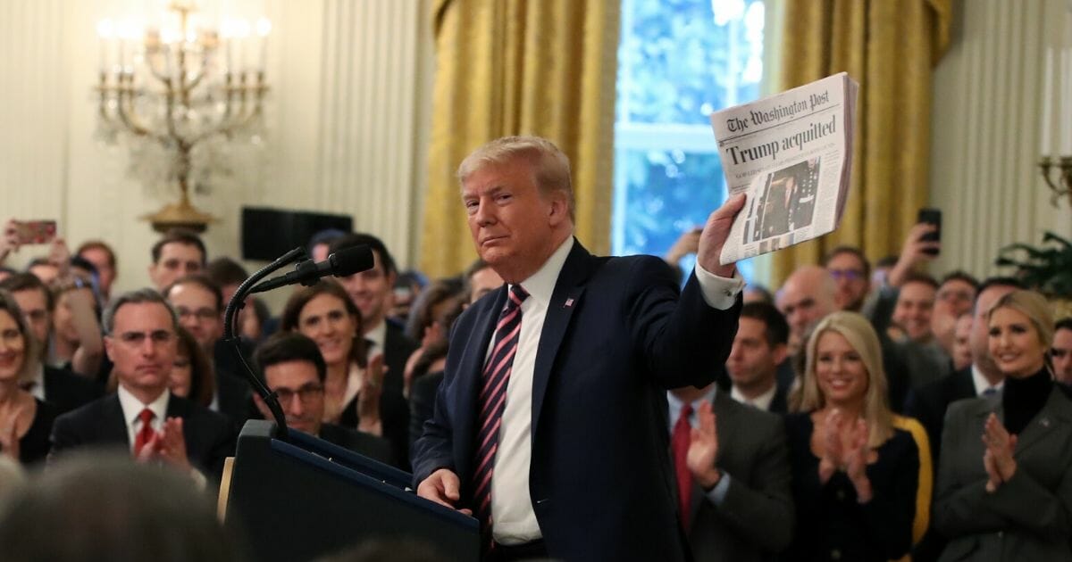 President Donald Trump holds up a newspaper as he speaks one day after the Senate acquitted him on two articles of impeachment in the East Room of the White House on Feb. 6, 2020 in Washington, D.C.