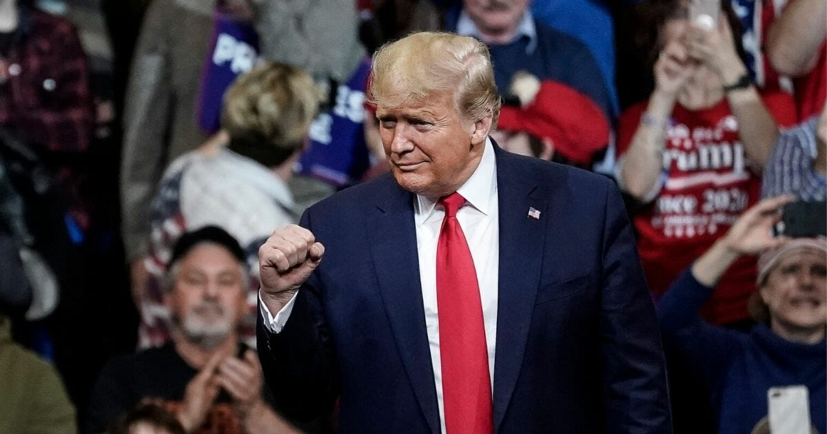 President Donald Trump pumps his fist as a crowd cheers.