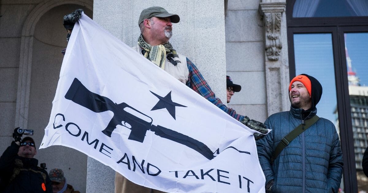 Gun rights hold a flag during the Jan. 20 demonstration in Richmond, Virginia, with an image of a rifle and the words "Come and Take It."