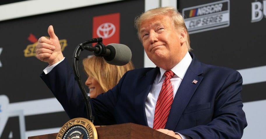 President Donald Trump speaks as first lady Melania Trump looks on from Victory Lane prior to the NASCAR Cup Series 62nd Annual Daytona 500 at Daytona International Speedway on Feb. 16, 2020 in Daytona Beach, Florida.