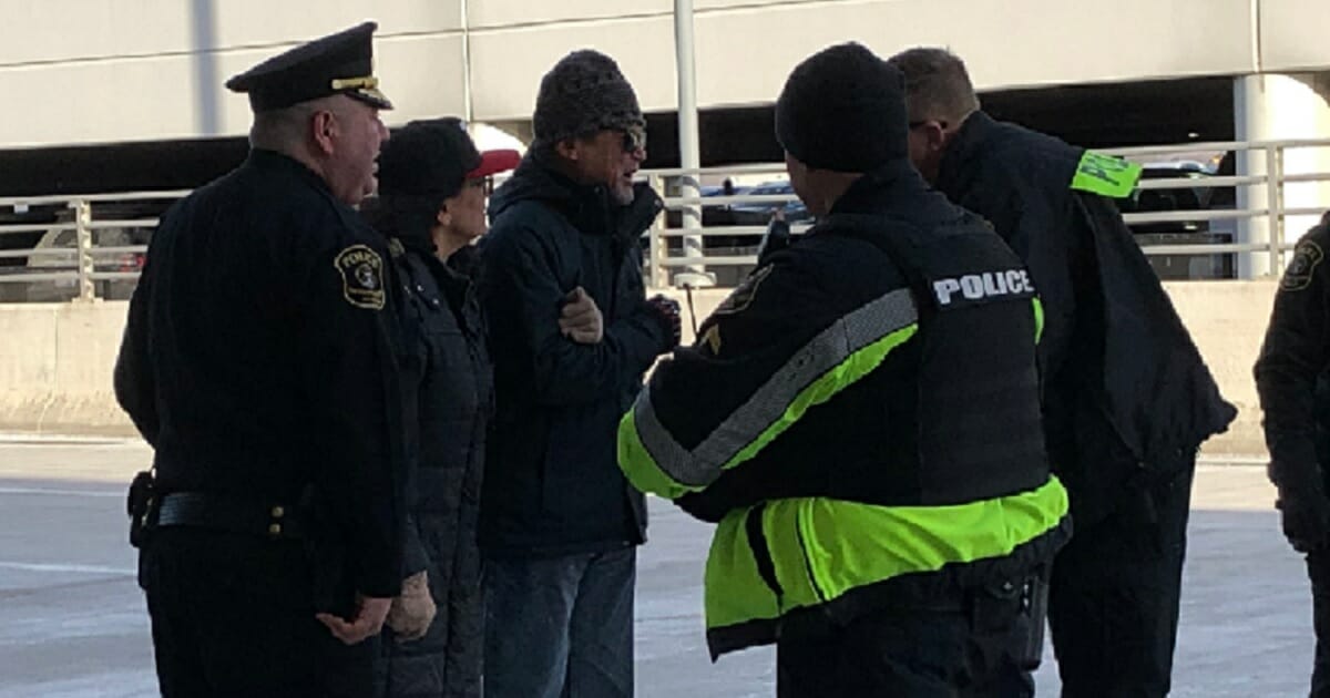 U.S., Rep. Rashida Tlaib, second from left, with police officers and demonstrators during a protests at Detroid Metropolitan Airport on Friday.