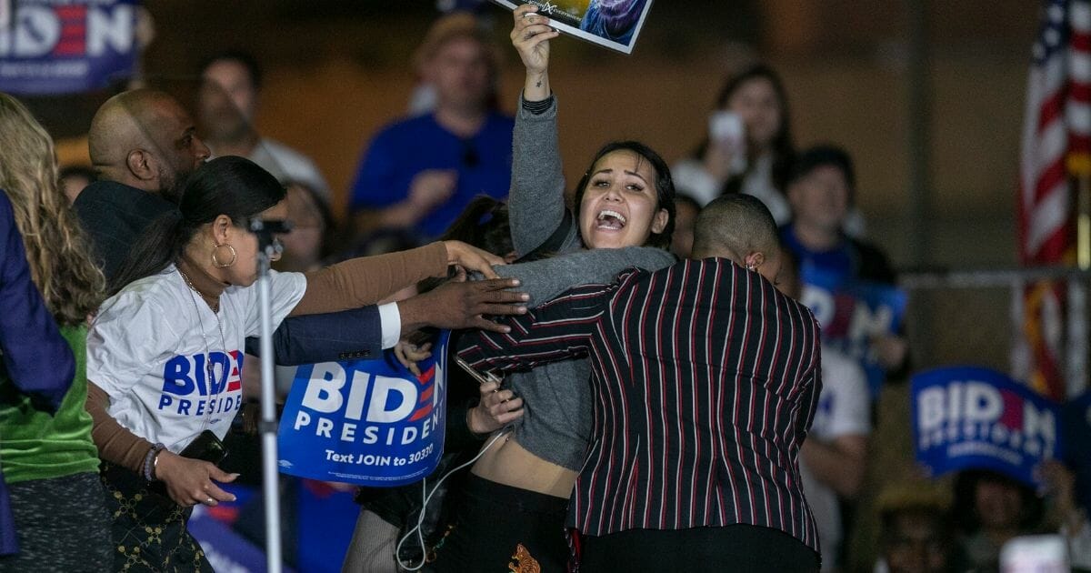 A woman charges the stage while holding a sign that reads "Let Dairy Die" as Democratic presidential candidate and former Vice President Joe Biden speaks at a Super Tuesday event at Baldwin Hills Recreation Center in Los Angeles, on M.arch 3, 2020