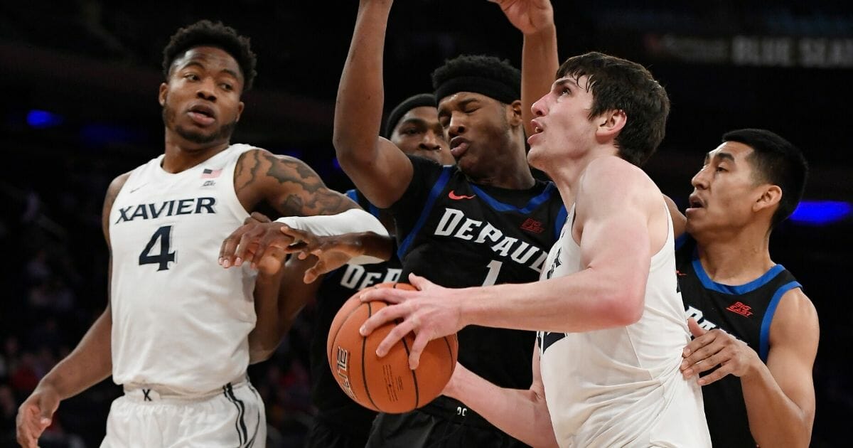 Zach Freemantle #32 of the Xavier Musketeers drives toward the basket as Romeo Weems #1 and Oscar Lopez Jr. #15 of the DePaul Blue Demons defend in the second half during the first round of the Big East Basketball Tournament at Madison Square Garden on March 11, 2020, in New York City.