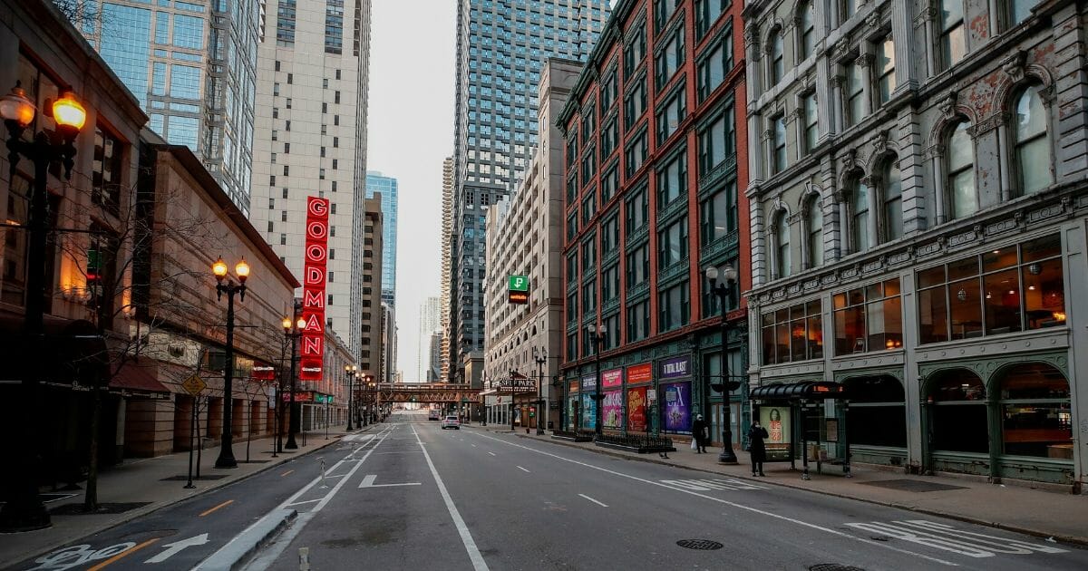 A woman waits for a bus on a nearly empty street in downtown Chicago on March 21, 2020. Millions of Americans have been confined to their homes amid the coronavirus pandemic.