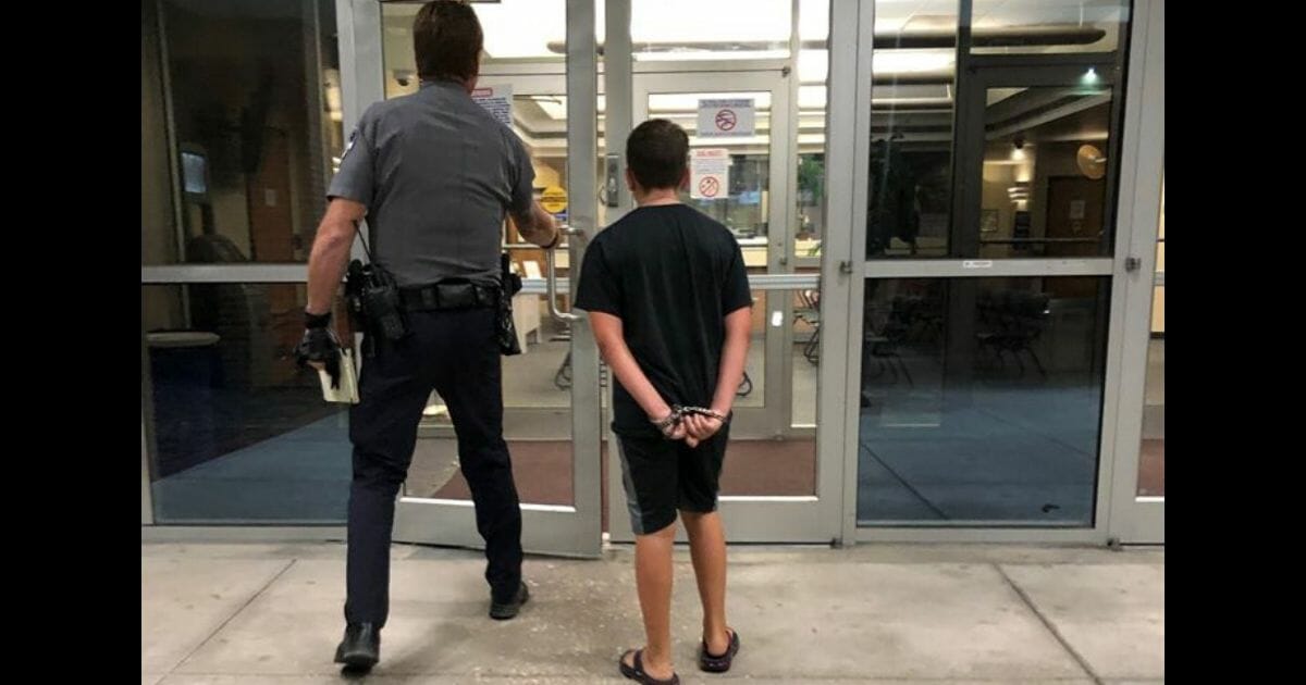 10-year-old Gavin Carpenter in handcuffs being escorted by a sheriff's deputy.