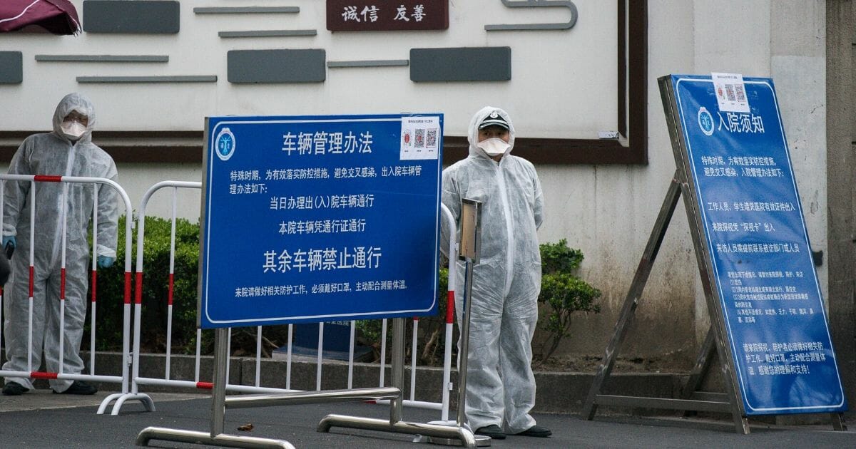 Workers wear protective masks and protective suits near the vehicle entrance of a hospital in Shanghai on March 2, 2020.