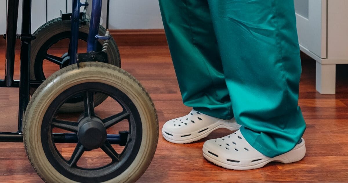 A person in scrubs wearing Crocs.