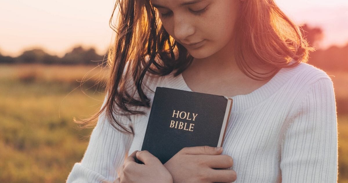 The image above is a stock photo of a girl holding a Bible.