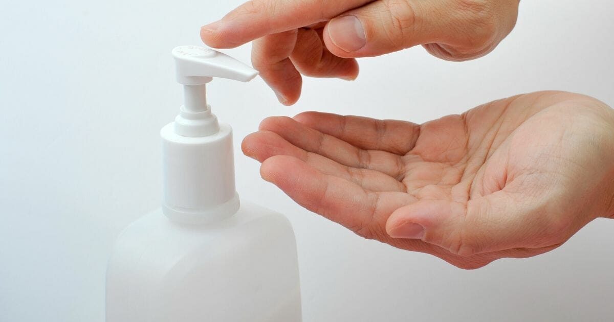 Hands accessing hand sanitizer, keeping clean for illness prevention.