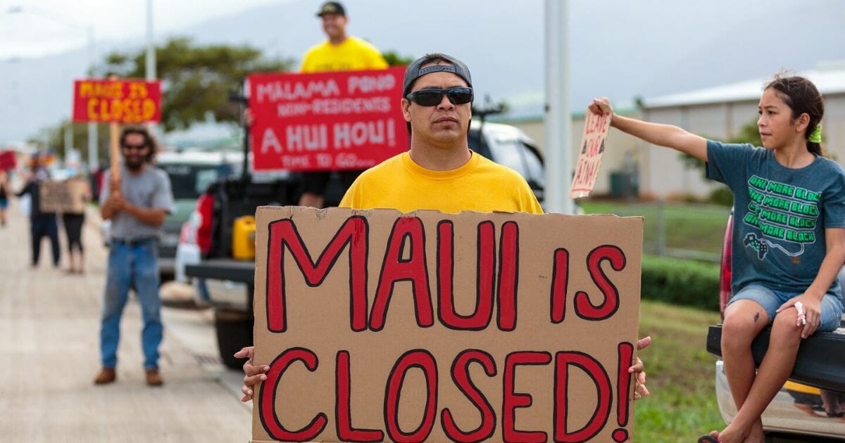 Hawaiians hold signs urging tourists to stay away.