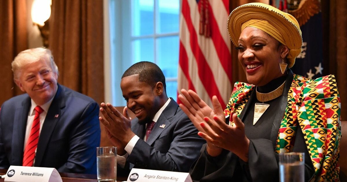 President Donald Trump smiles during a meeting with Terrence Williams, center, Angela Stanton-King, right, and other African-American leaders in the Cabinet Room of the White House on Feb. 27, 2020.