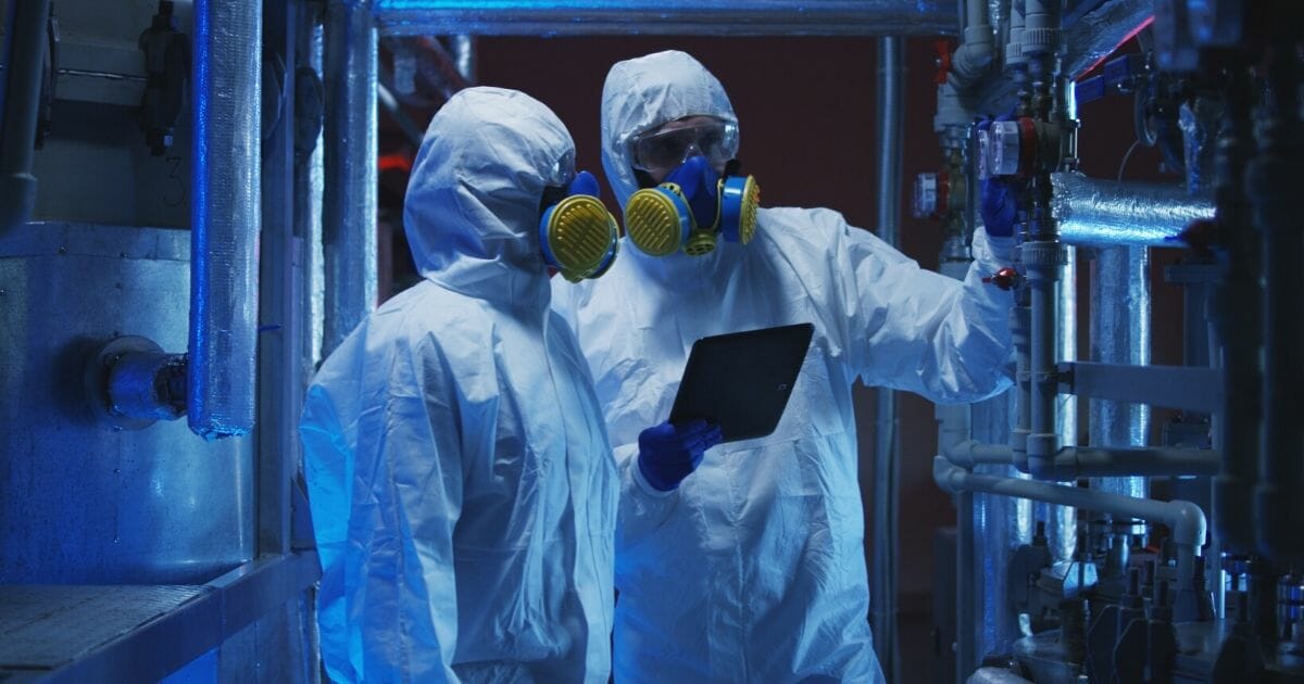 Stock image of two scientists in hazmat suits conducting maintenance work.