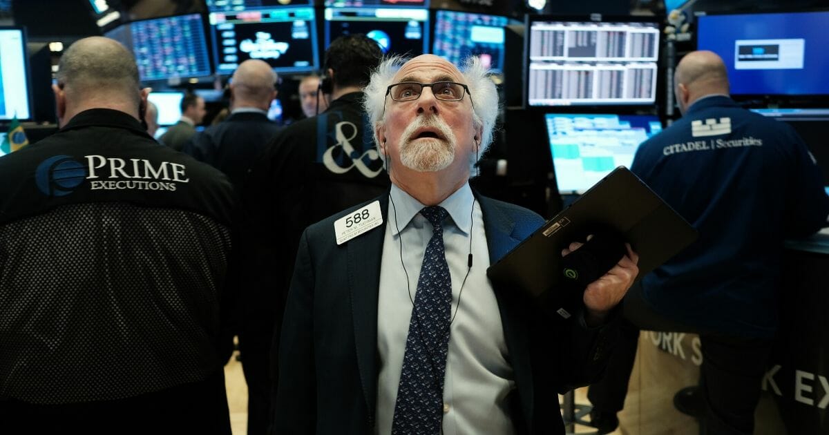 A trader on the floor of the New York Stock Exchange reacts Monday to plunging stock prices that forced a 15-minute halt to trading.
