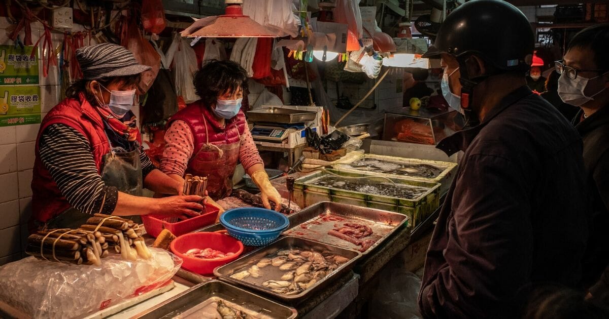 Buyers wearing face masks purchase seafood from masked vendors at a wet market in Macau, China, in January.