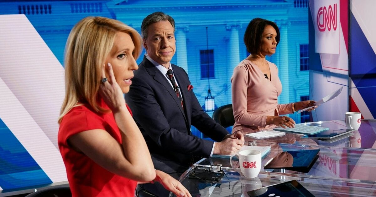 CNN news anchor Jake Tapper, center, flanked by Univision news anchor Ilia Calderón, right, watches as co-anchor Dana Bash adjusts her ear piece before the start of the 11th Democratic Party 2020 presidential debate with former Vice President Joe Biden and Vermont Sen. Bernie Sanders in a CNN Washington Bureau studio in Washington, D.C., on March 15, 2020.