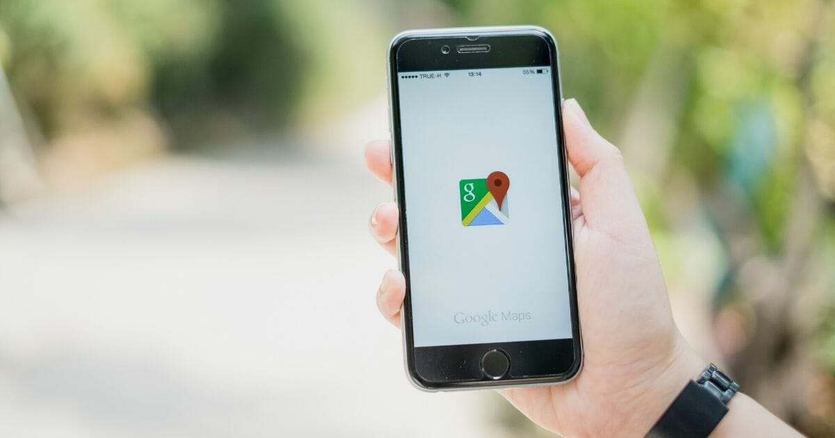 Stock image of a man holding a phone with the Google Maps app.