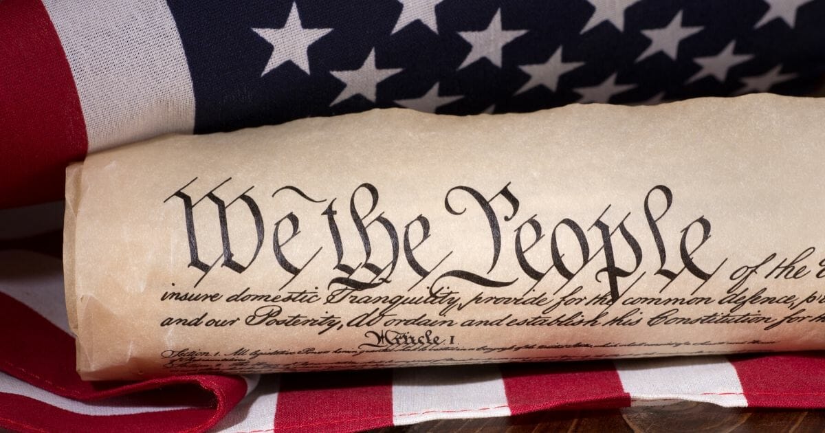 Stock image of the text of the preamble to the United States Constitution with an American flag in the background.