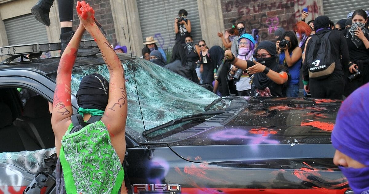Demonstrators smash a car during a march to commemorate International Women's Day in Mexico City on March 8, 2020.