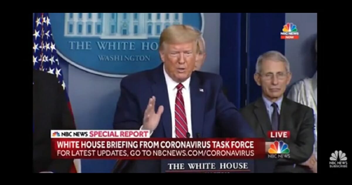 Dr. Anthony Fauci, director of the National Institute for Allergy and Infectious Diseases, stands behind President Donald Trump at a news briefing on Friday at the White House.