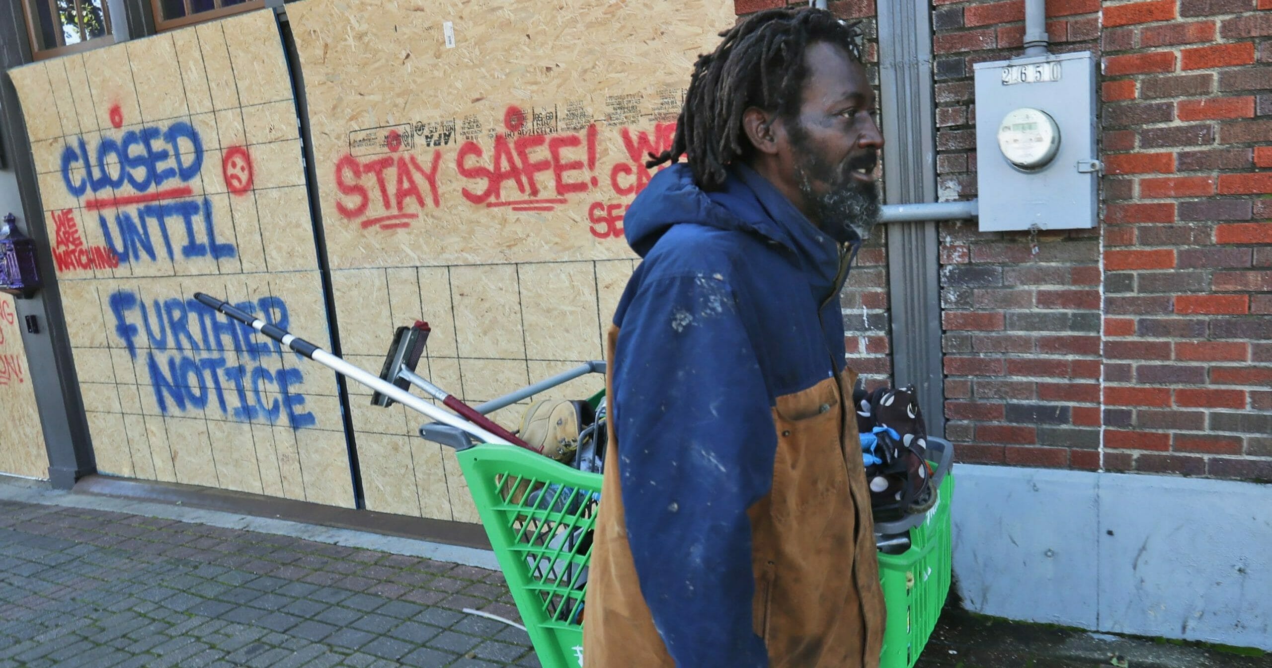 In this March 31, 2020, file photo, Vincent Amos, who identified himself as homeless, pulls a shopping cart with his belongings amid businesses closed by concerns of the COVID-19 coronavirus in the Deep Ellum section of Dallas.