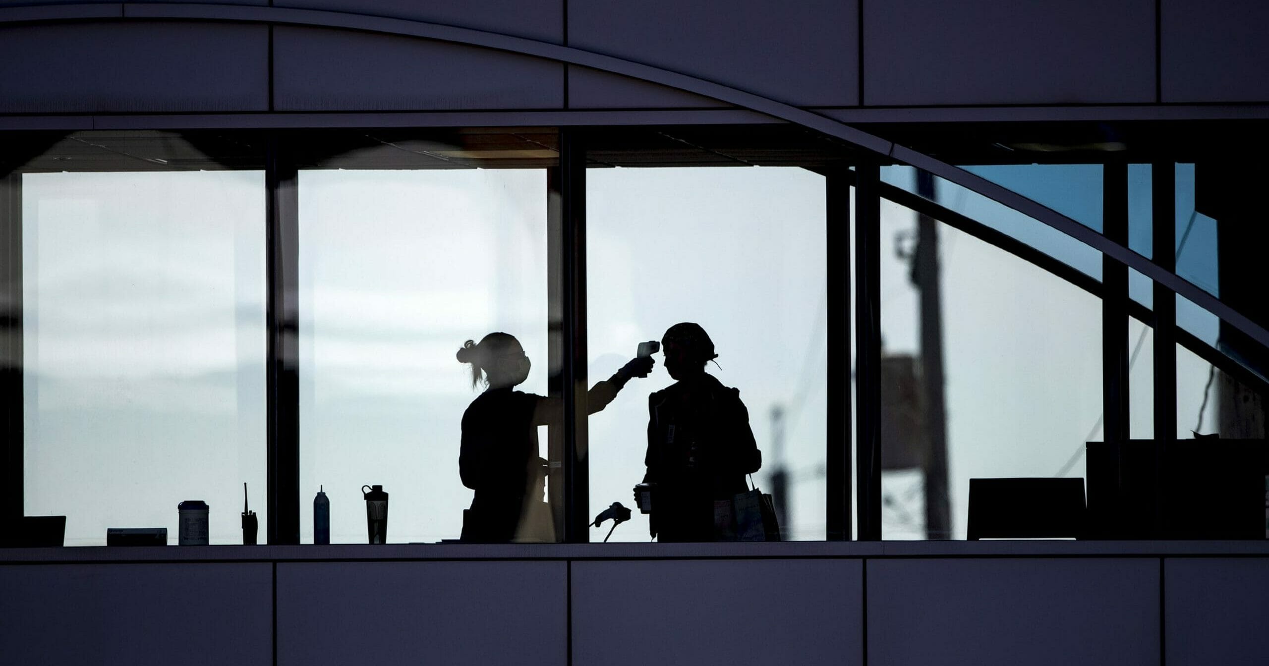 Amid coronavirus concerns, a health care worker takes the temperature of a visitor to Essentia Health in Duluth, Minnesota, who was crossing over a skywalk bridge from the adjoining parking deck April 10, 2020.