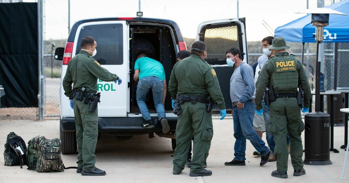 U.S. Border Patrol agents use personal protective equipment as they prepare to transport a group of individuals encountered near Sasabe, Arizona, to the U.S.-Mexico border on March 22, 2020.