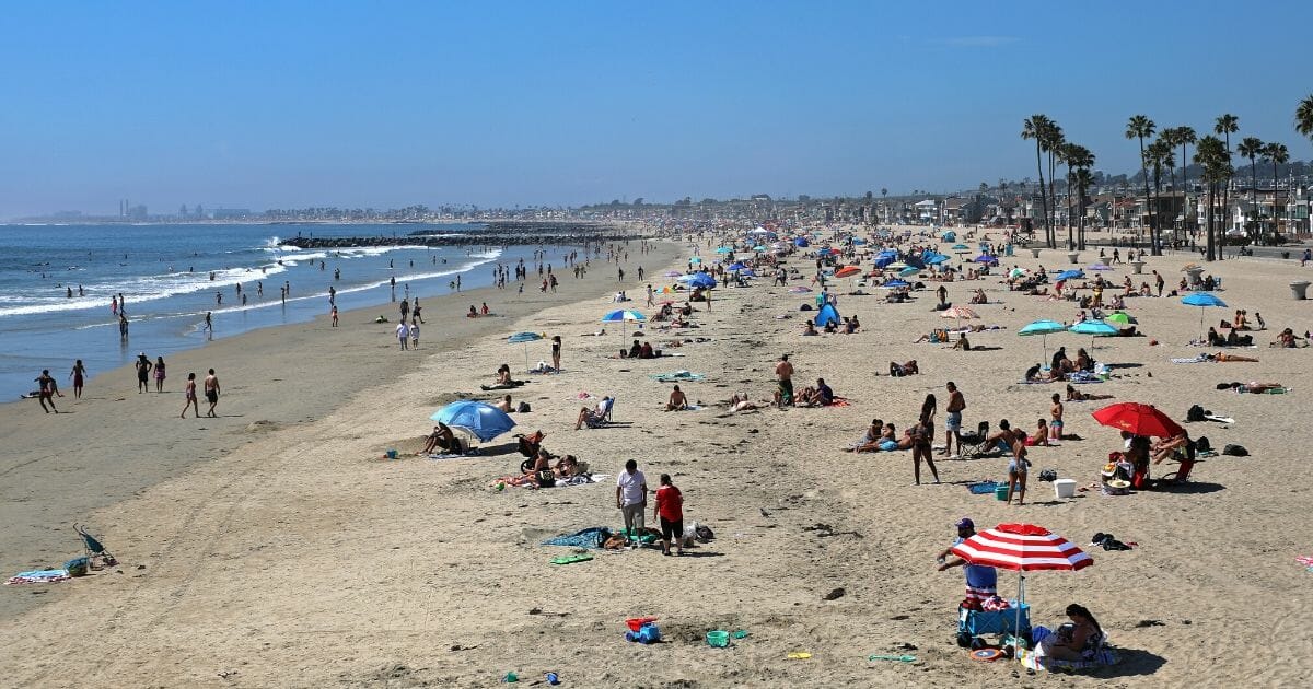 People enjoy the sun, surf and sand north of Newport Beach Pier in California on April 25, 2020.