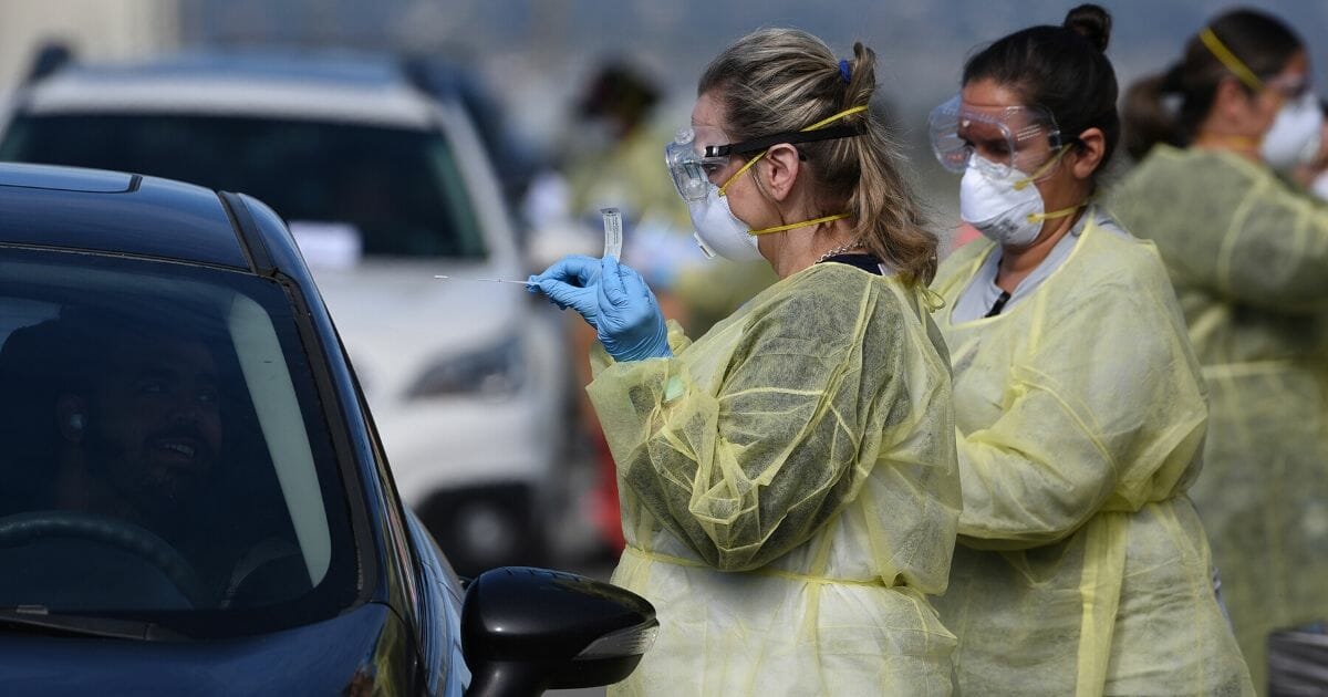 Medical personnel from Riverside University Health Systems hospitals administer a coronavirus test to an individual during drive-through testing in the parking lot of Diamond Stadium on March 22, 2020, in Lake Elsinore, California.