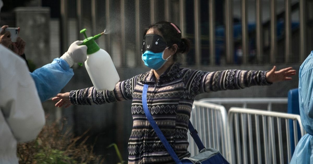 Doctors disinfect a discharged COVID-19 patient while she leaves Wuchang Fang Cang makeshift hospital on March 10, 2020, in Wuhan, Hubei province, China.