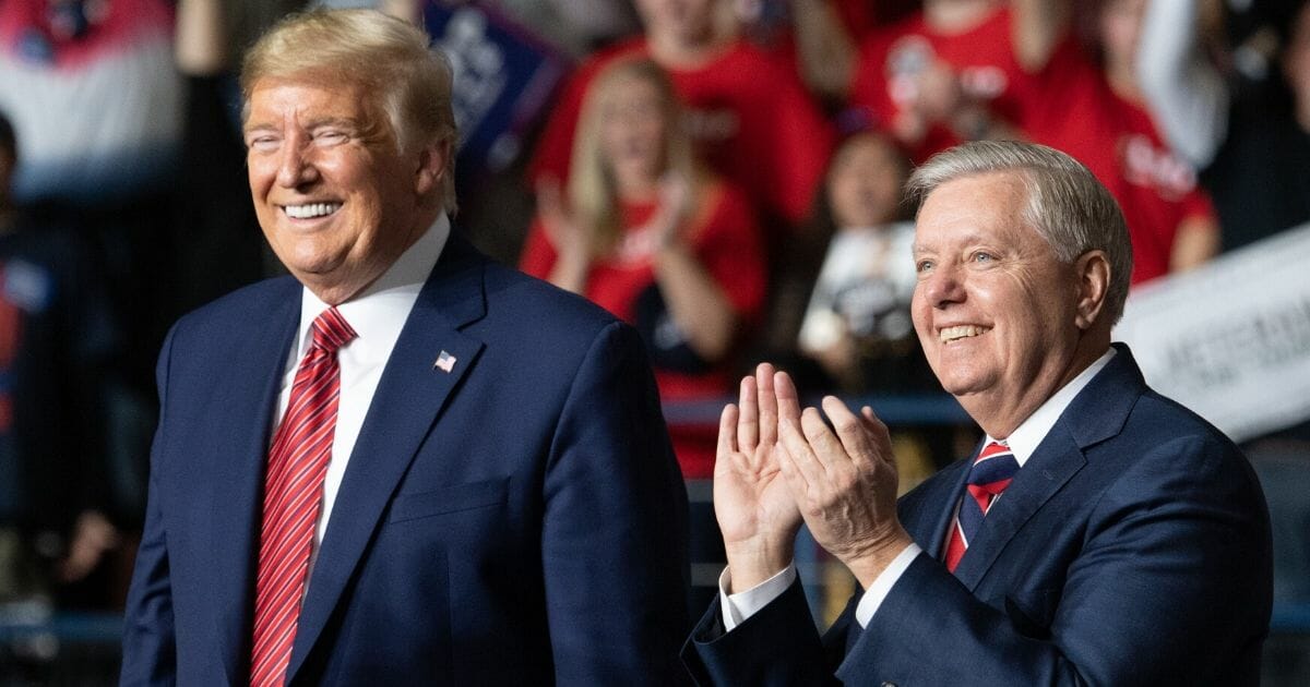 President Donald Trump smiles as he stands alongside Sen. Lindsey Graham during a rally at the North Charleston Coliseum in North Charleston, South Carolina, on Feb. 28, 2020.