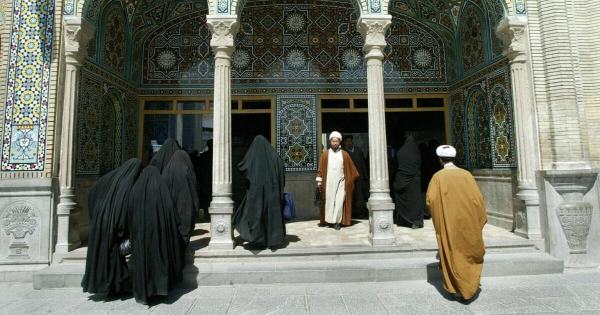 Iranian clerics walk at the courtyard of the holy shrine of Fatima Masumeh in the holy city of Qom on April 26, 2004.