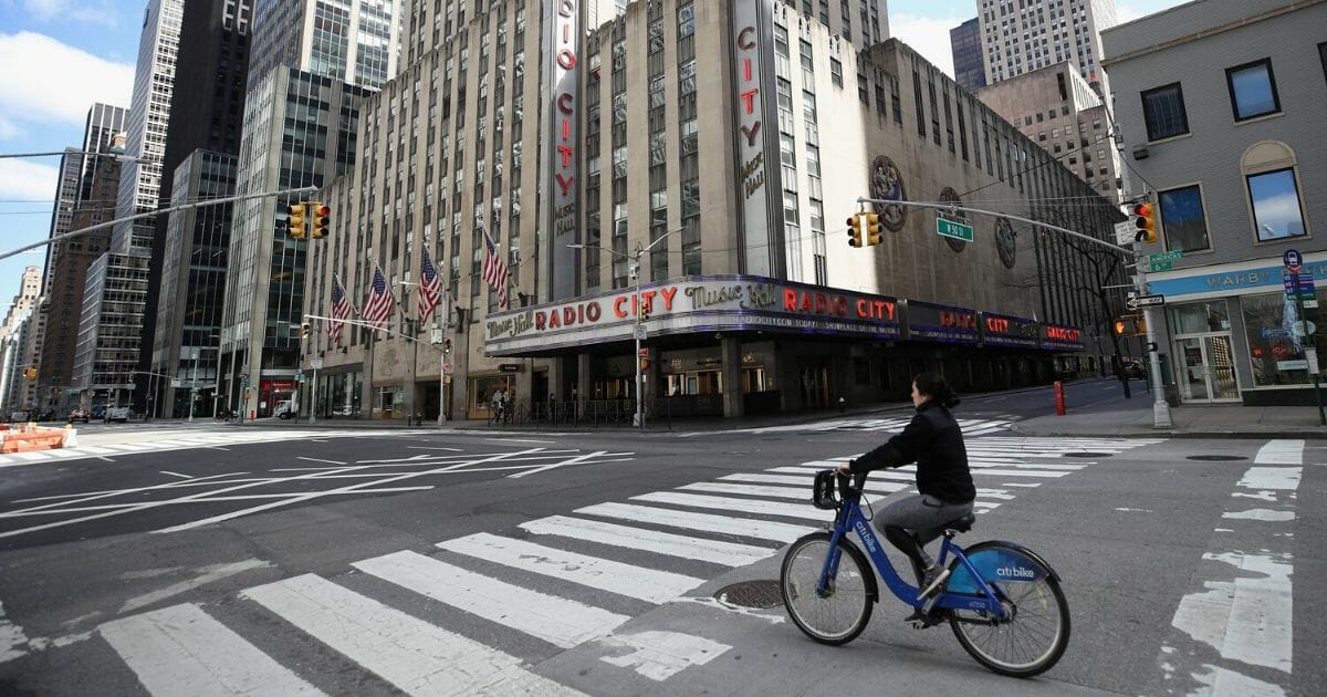 A bicyclist moves past Radio City Music Hall on the nearly empty streets of New York City on April 2, 2020.