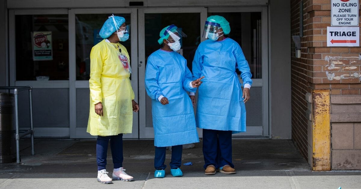 Three emergency room nurses stand outside the Maimonides Medical Center waiting for a midday food delivery on April 7, 2020, in the Brooklyn borough of New York City.