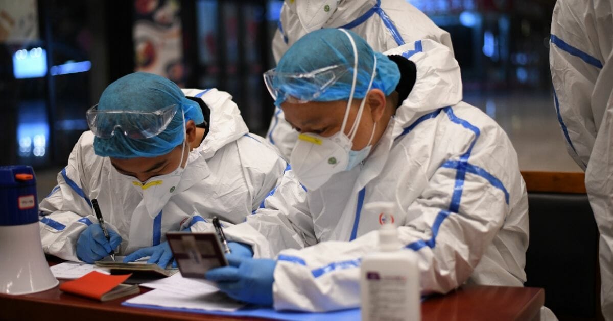 Chinese security officers garbed in hazmat suits check internal passports at the Wuhan train station in Wuhan, China.