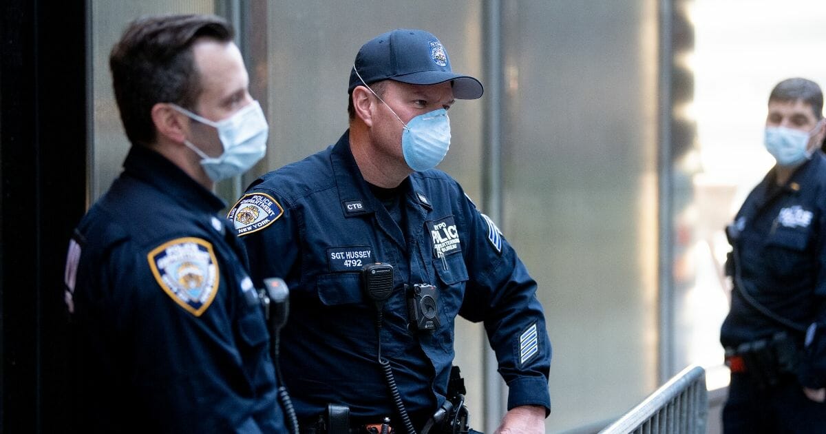Police wearing surgical masks stand guard outside New York City's Trump Tower on Sunday.