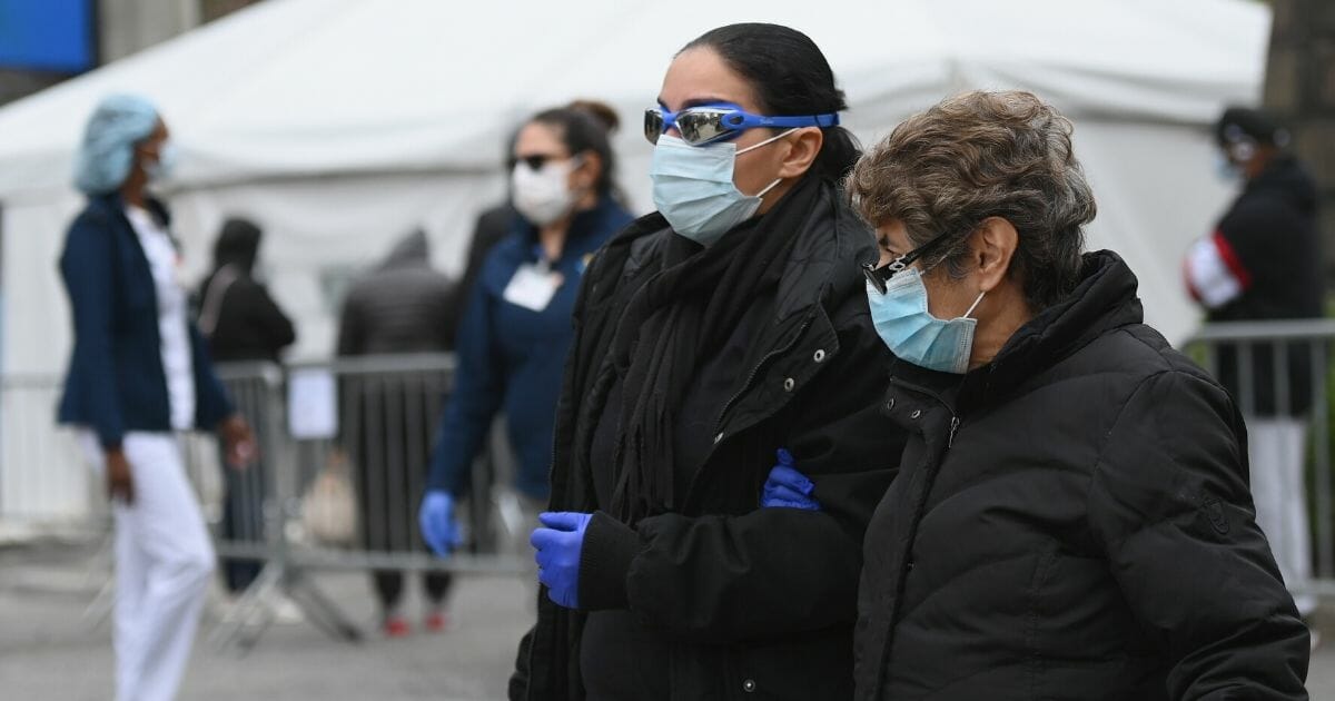 Masked pedestrians pass a a COVID-19 screening tent outside the Brooklyn Hospital Center in New York on March 20.