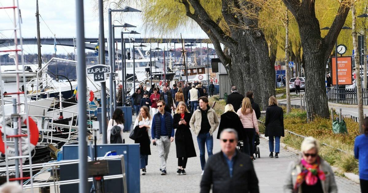 People walk along Norr Mälarstrand street in Stockholm on April 19, 2020.