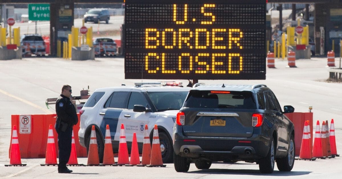 Customs officers speak with people in a car beside a sign saying that the U.S. border is closed at the U.S.-Canada border in Lansdowne, Ontario, on March 22, 2020.