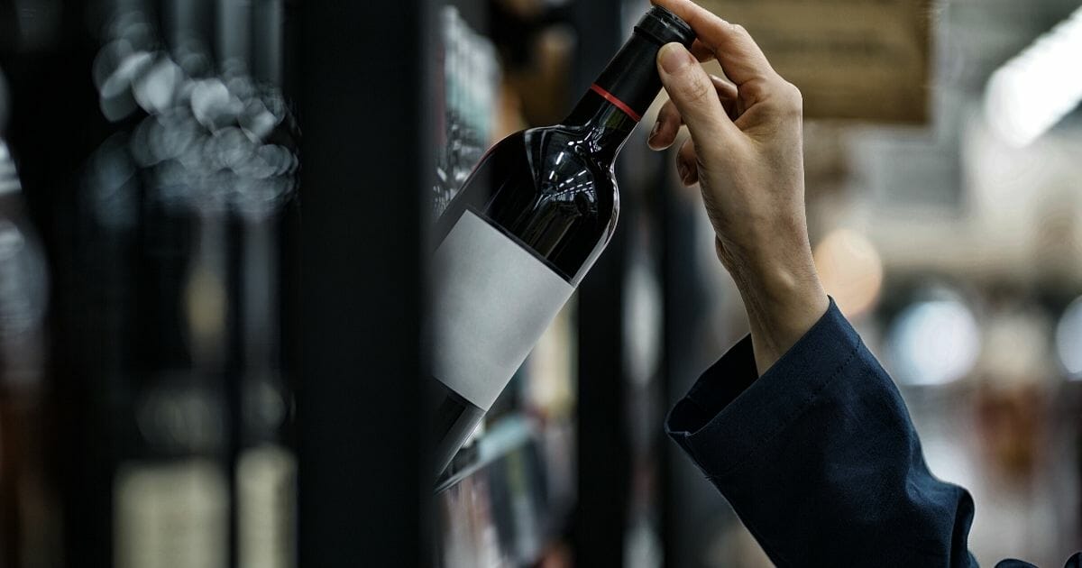 Wine bottle being pulled from shelf.