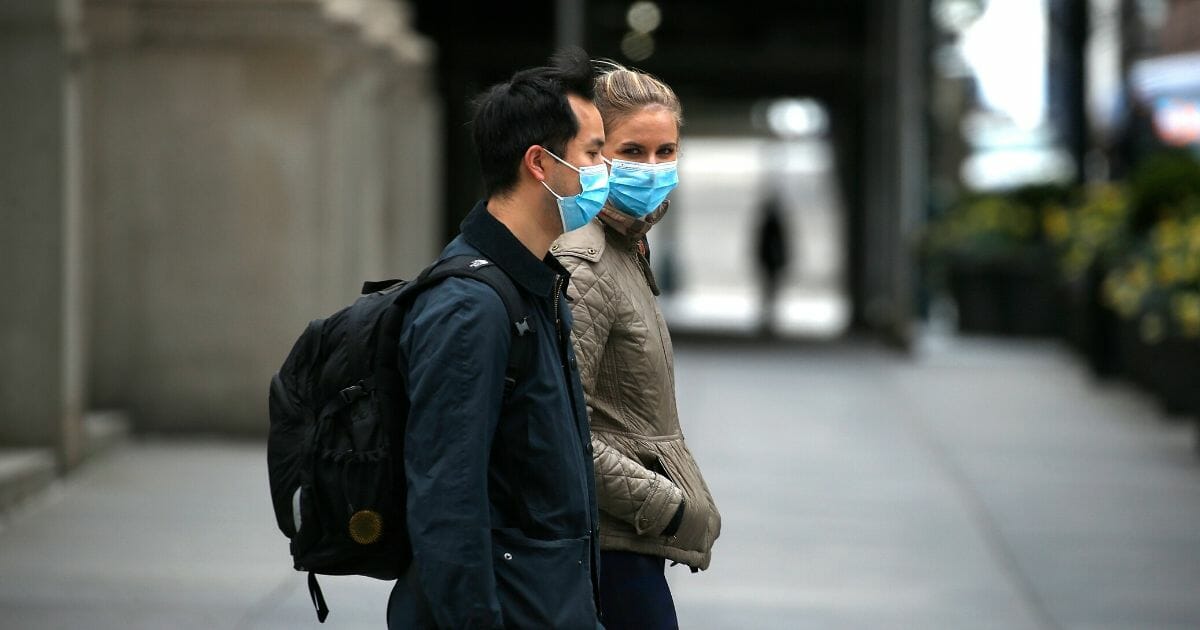 Two people wearing protective masks on a walk during the coronavirus pandemic on April 18, 2020, in New York City.