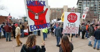 People hold signs during a protest against Wisconsin's coronavirus shutdown in front of the State Capitol in Madison on April 24, 2020.